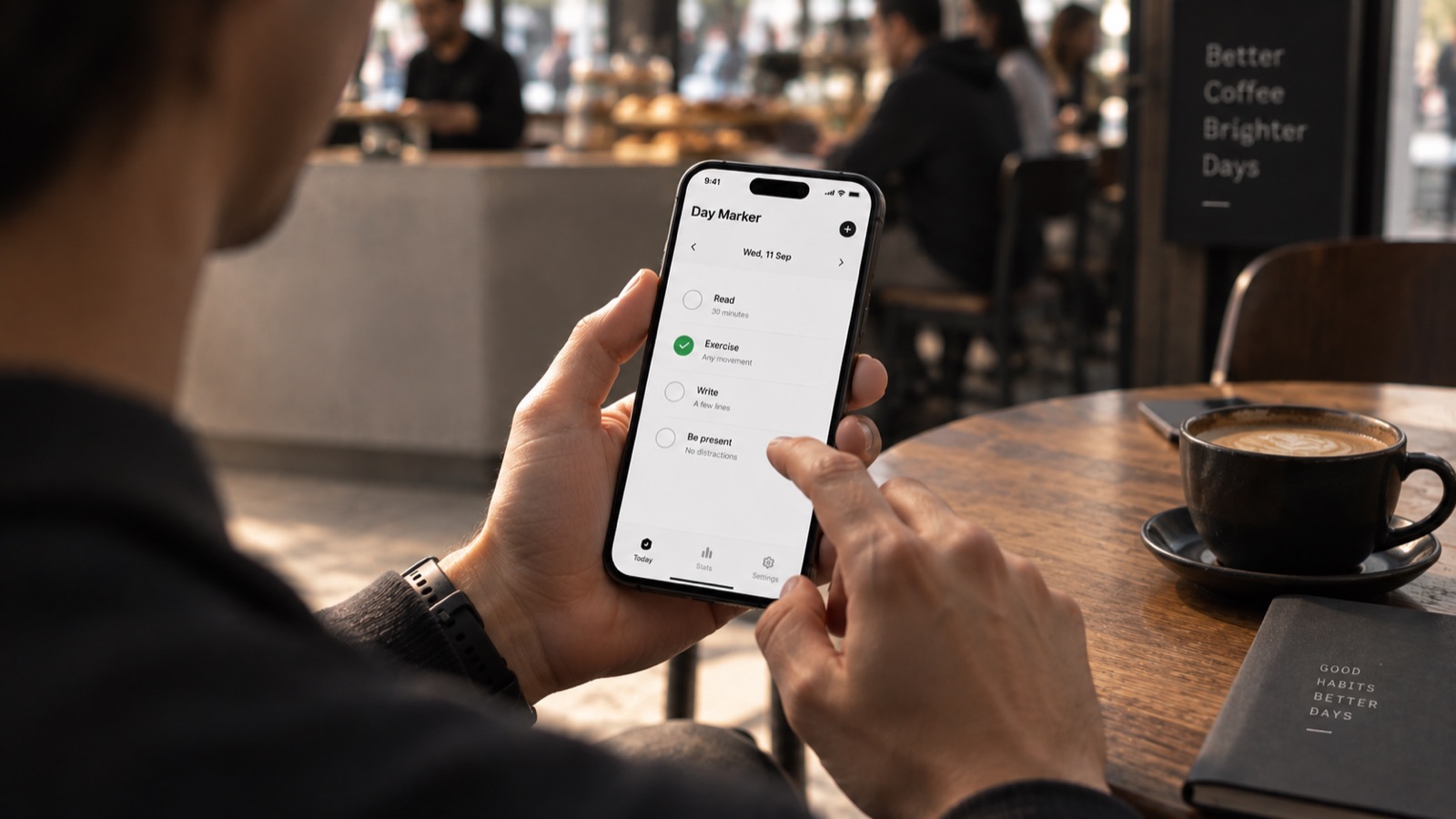 A hand holding a phone in a real-world moment—waiting in line, holding coffee—glancing at the app for a few seconds